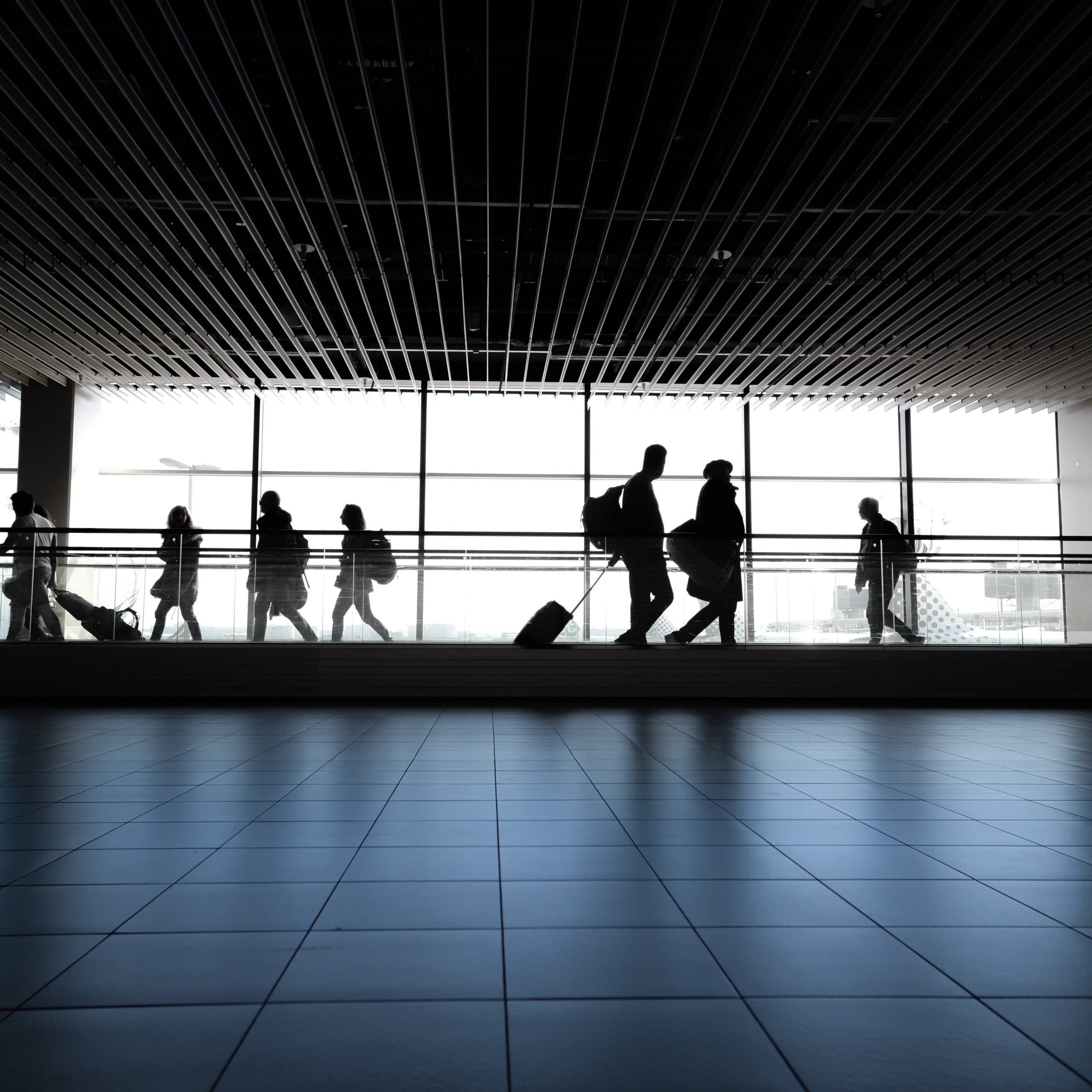 Traveler walking through an airport terminal with luggage, representing budget-conscious flight planning