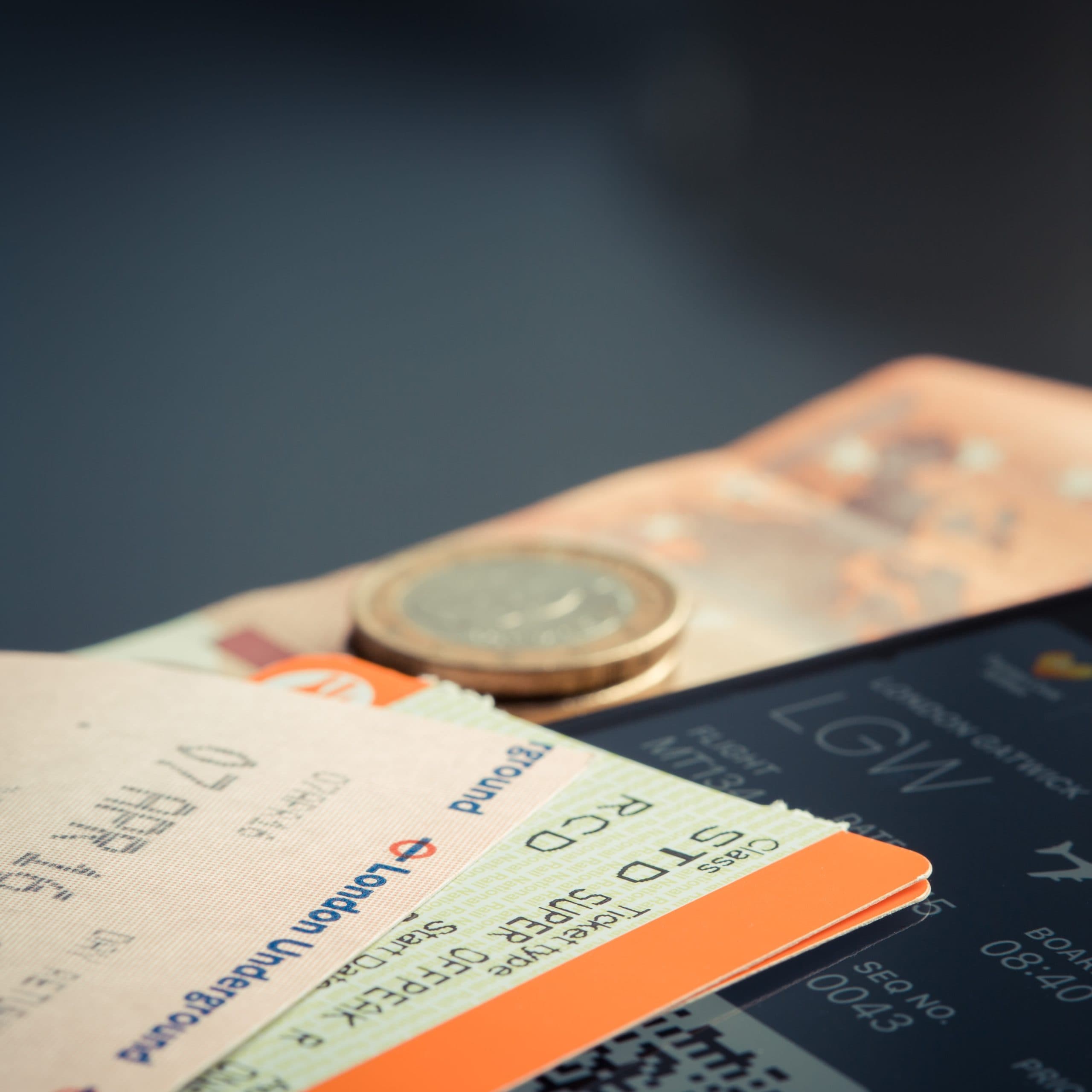 Close-up of a London Underground ticket, a coin, and an airline boarding pass to Gatwick laid together, representing separate tickets combined for one trip